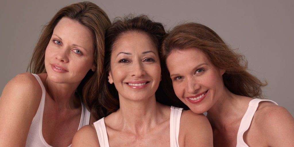 three women together facing forward smiling at camera
